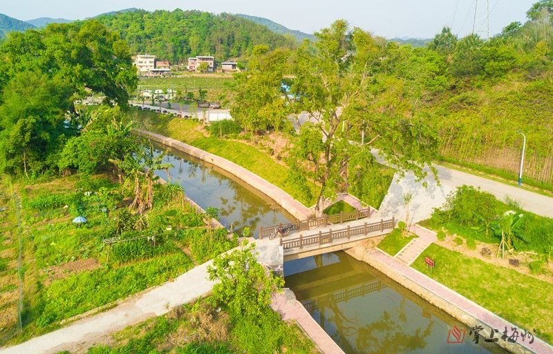 在梅江区城北镇扎上村,流水潺潺,水车转动,两岸郁葱,三五村民正在扎田