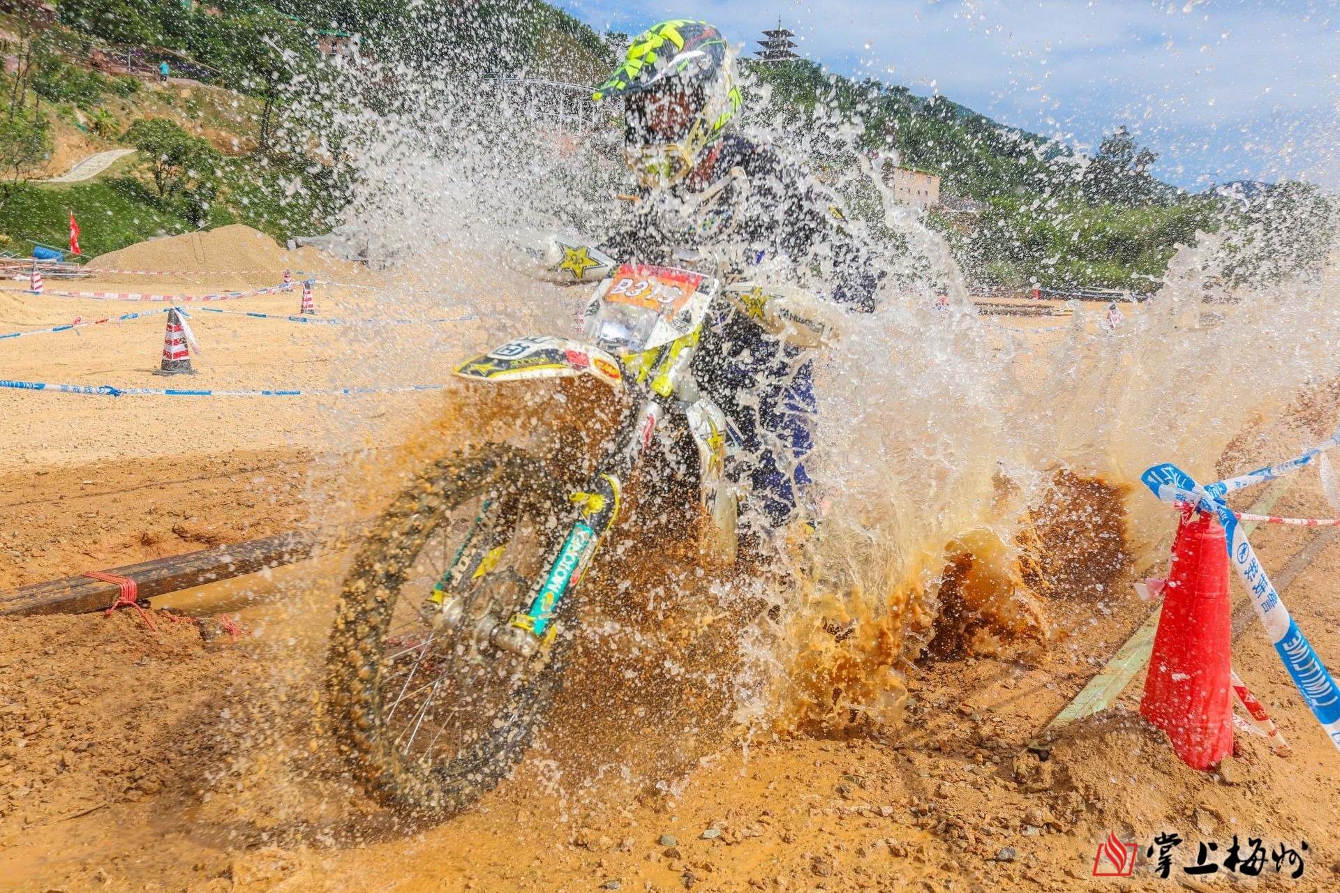 一位车手不慎掉下独木桥,泥塘里的水被突如其来的摩托车喷溅而出.