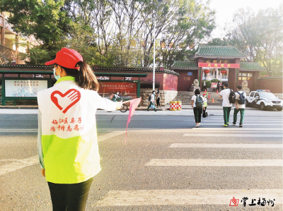 返校路上，志愿者挥动爱心小红旗为学子护航